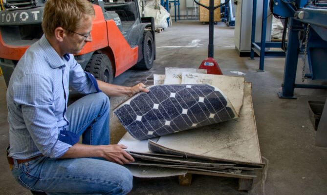 Ze solárních panelů nejdříve pracovníci linky odstraní hliníkové rámy a kabeláž, jak ukazuje Vojtěch Musil. Foto: Karolína Chlumecká, Ekonews